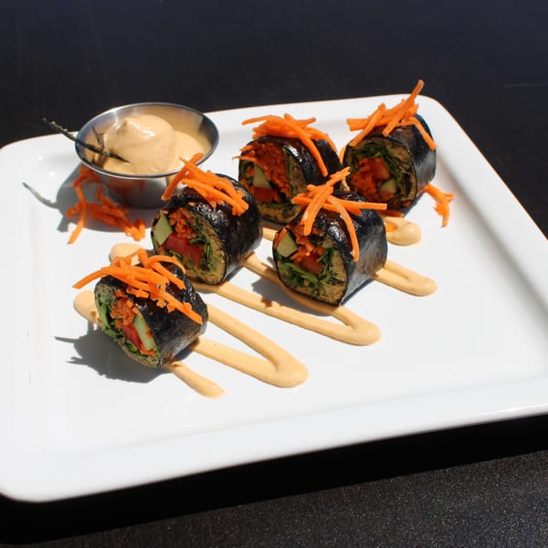 Five Garden Kitchen healthy sushi rolls with shredded carrots and a side of sauce.